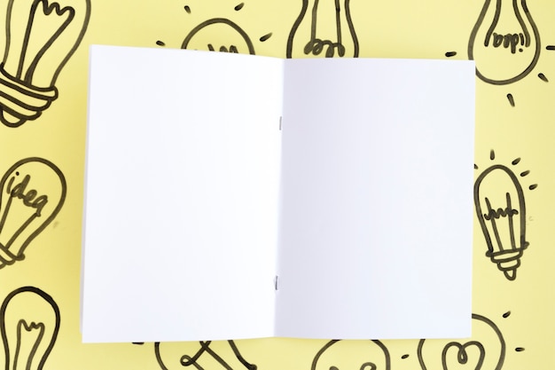 Free photo blank white page on hand drawn light bulb over the yellow background