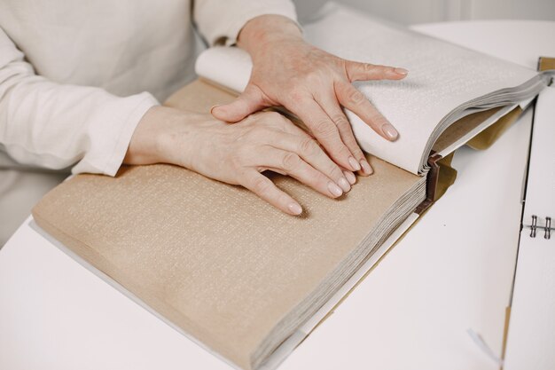 Blind mature woman reading braille book at home