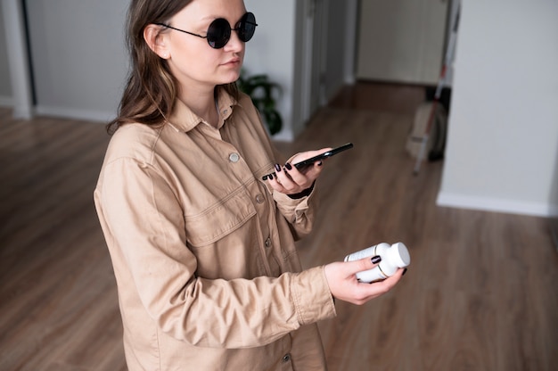 Free photo blind woman using her smartphone to read a drug container