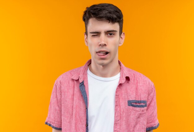 Blinked caucasian young man wearing pink shirt on isolated orange wall