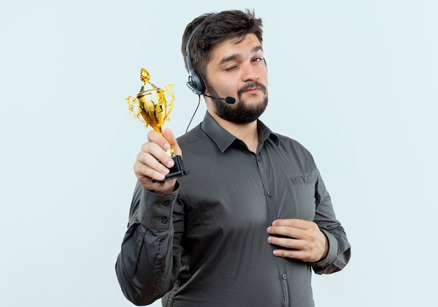 Free photo blinked young call center man wearing headset holding winner cup isolated on white background