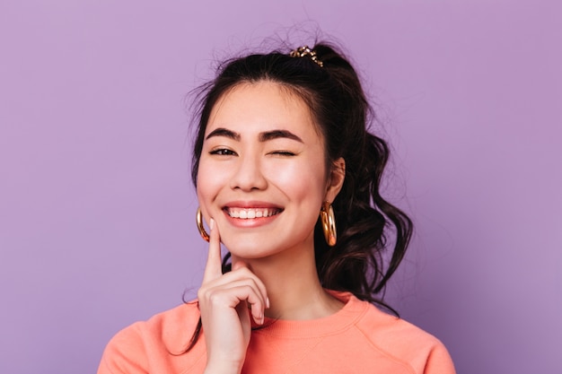 Blissful asian woman with curly hair making funny faces. Studio shot of glad korean young woman.