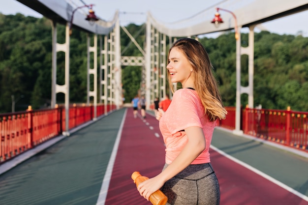 Blissful female runner enjoying good morning. Outdoor portrait of cute white girl running at stadium.