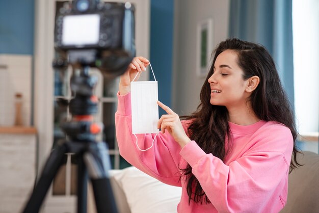 Blogger pointing at surgical mask in front of camera