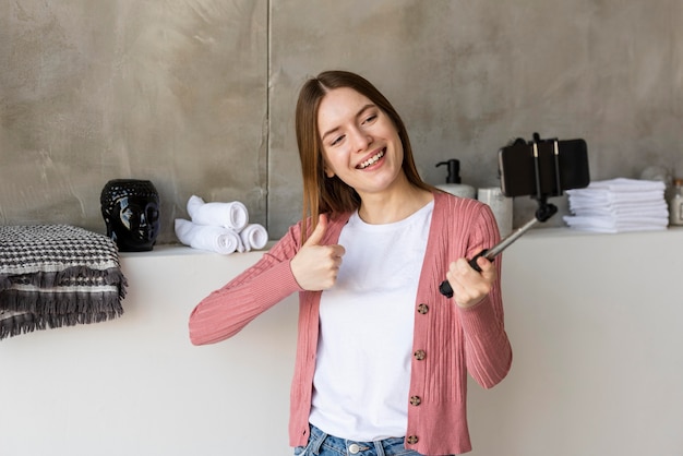 Free photo blogger recording herself showing home decor and thumb up