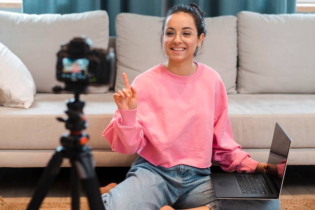 Blogger recording herself with glasses holding laptop