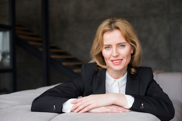 Free photo blond business woman sitting on couch and smiling