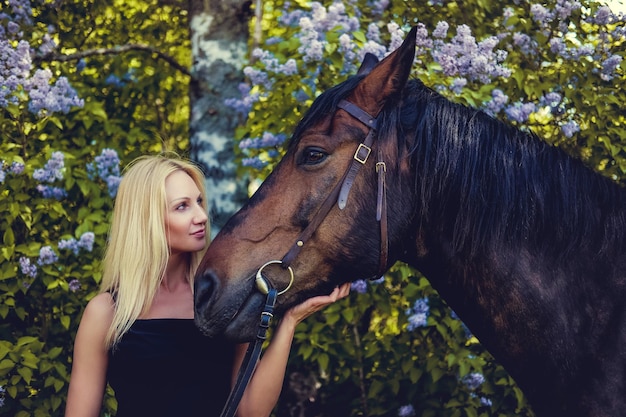 Free Photo blond female in black evening dress posing with brown horse.