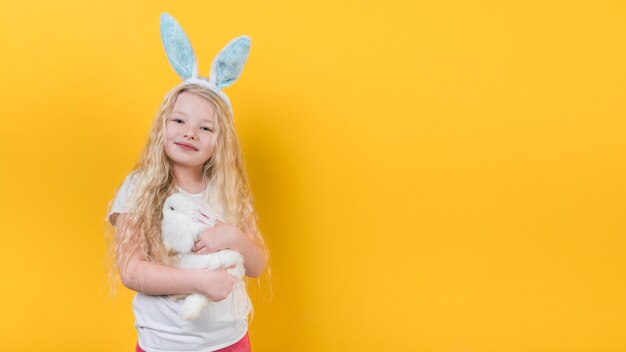 Blond girl in bunny ears with rabbit 