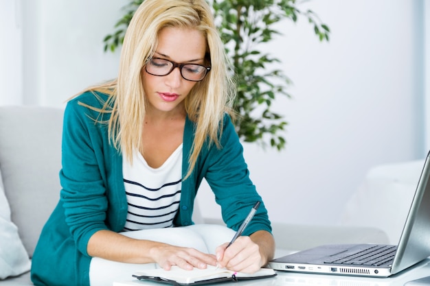 Blond girl writing something with laptop on