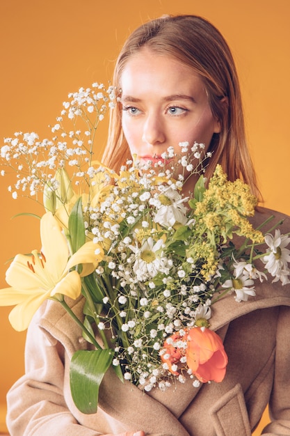 Blond woman standing with flowers bouquet in coat