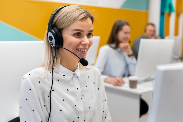 Blond woman working in a call center with headphones and computer