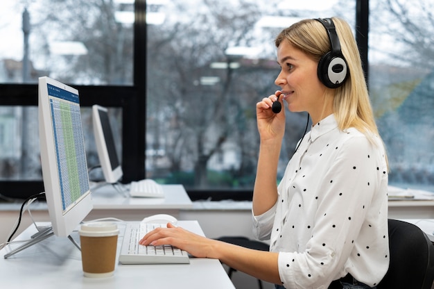 Free Photo blond woman working in a call center with headphones and computer