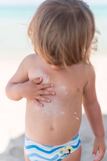 Blonde child at the beach looking down medium shot