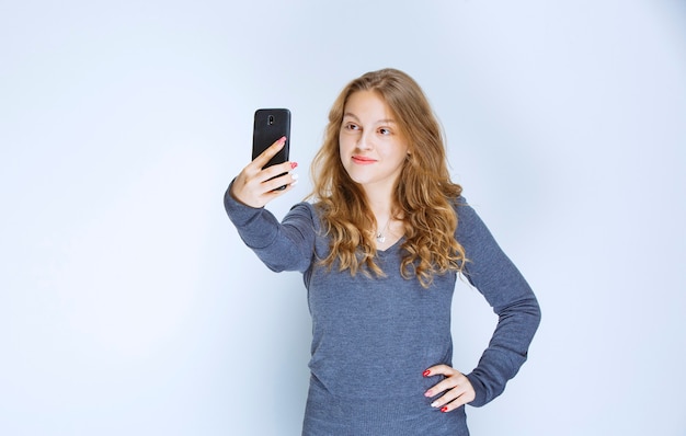 Blonde curly haired girl taking her selfie.