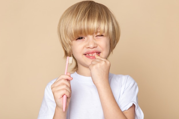 blonde cute boy sweet holding toothbrush on pink desk