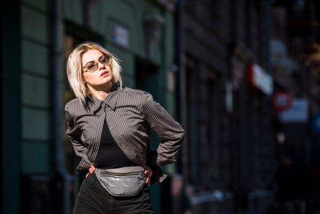 Blonde fashionable young woman with hand on hips looking away