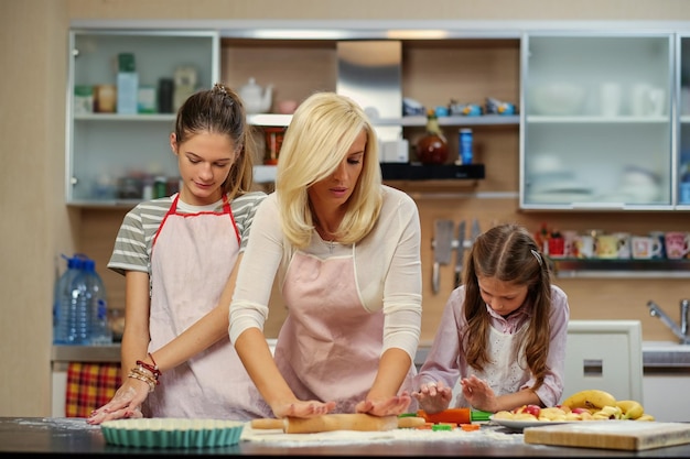 Free Photo blonde female and two teenage girls showing how to dough in the home kitchen.