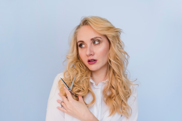 Blonde girl cutting of her hair