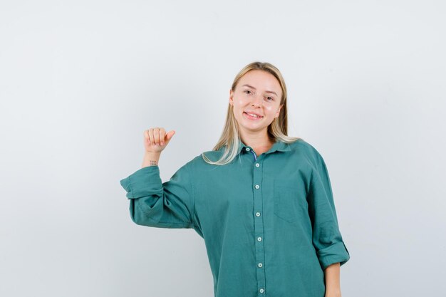 Blonde girl in green blouse clenching fist and looking happy