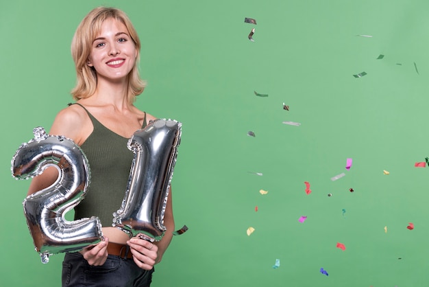 Free photo blonde girl holding a 21 balloon sign