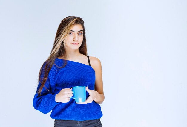 Blonde girl holding a blue coffee mug.