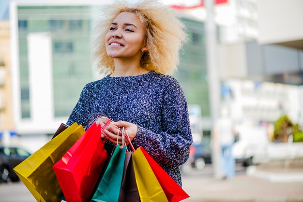 Blonde girl holding shopping bags smiling