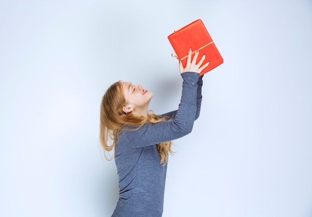 Free Photo blonde girl hugging her red gift box and feeling happy.