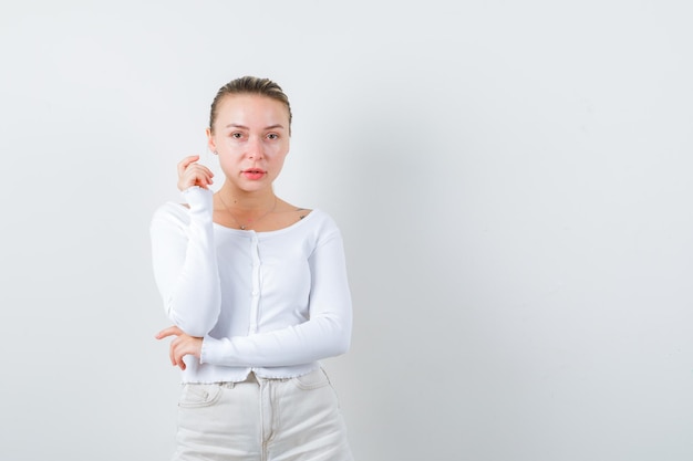 Blonde girl is posing for camera on white background