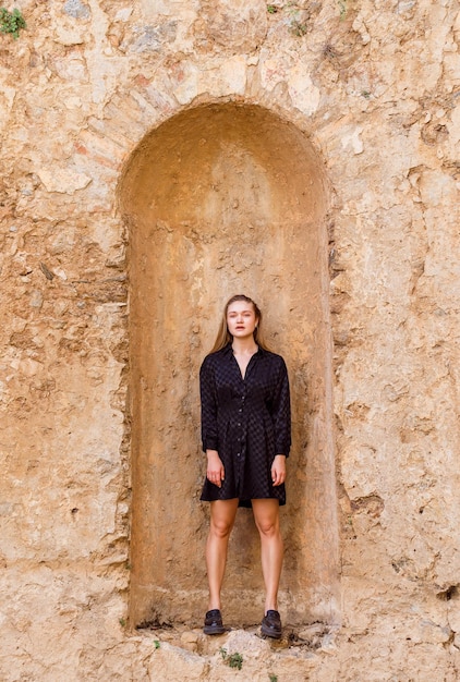 The blonde girl look at the left in black dress on stone background