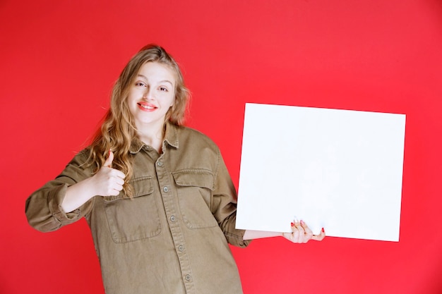 Blonde girl looking to a canvas and enjoying it.