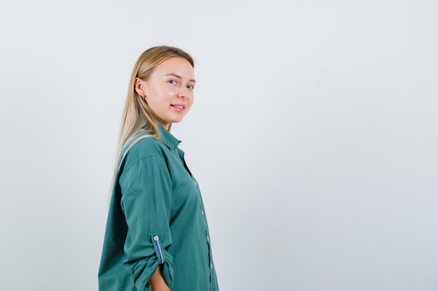 Free photo blonde girl looking over shoulder in green blouse and looking enchanting