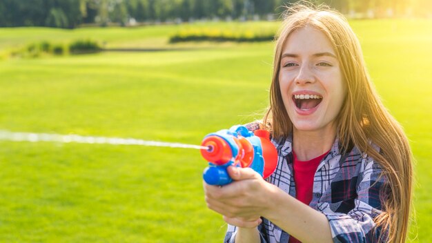 Blonde girl playing with water gun