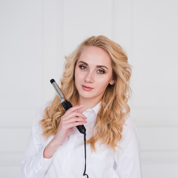 Blonde girl posing with curling iron