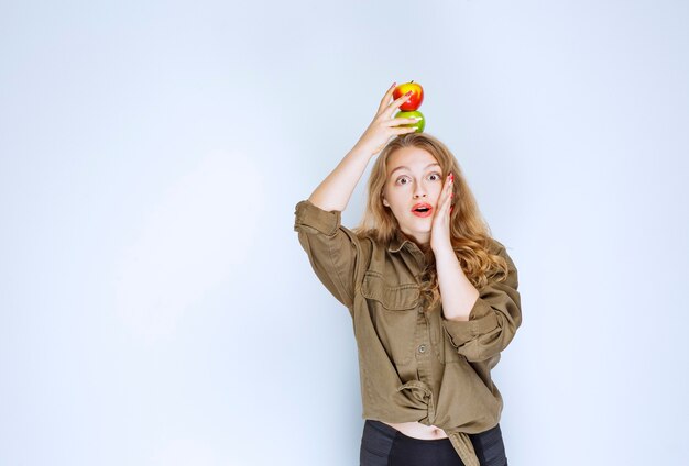 Blonde girl putting a red peach over her head.