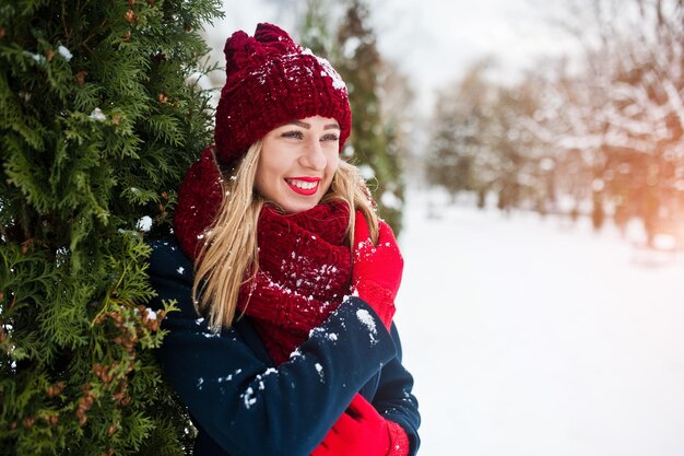 Blonde girl in red scarf and coat walking at park on winter day