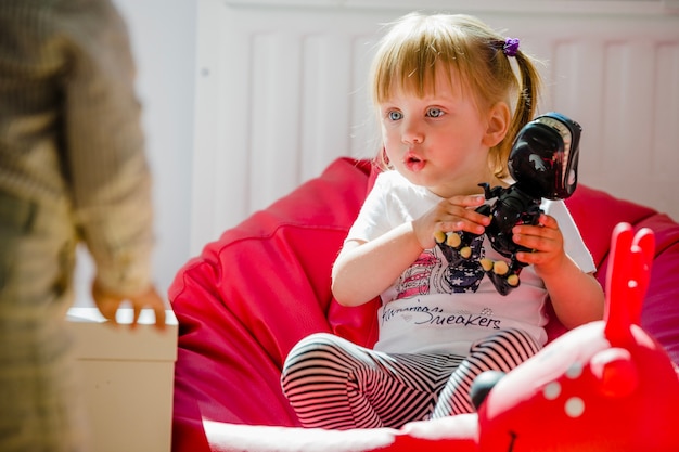 Free photo blonde girl sitting in chair with dinosaur