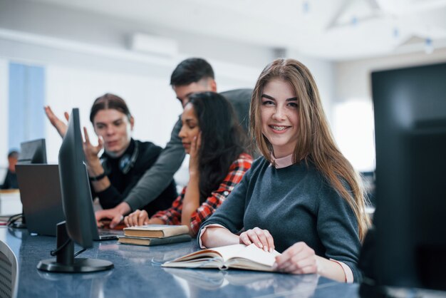 Blonde girl smiling. Group of young people in casual clothes working in the modern office