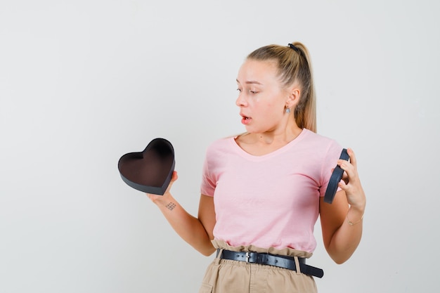 Free Photo blonde girl in t-shirt, pants looking at empty gift box and looking surprised, front view.