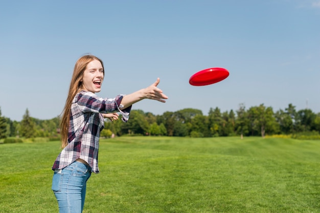 Free photo blonde girl throwing a red frisbee