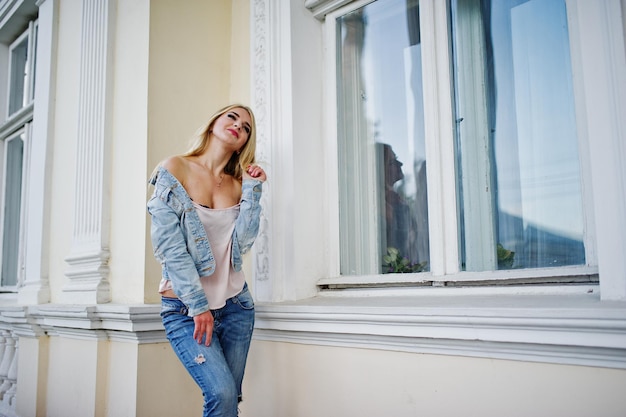 Blonde girl wear on jeans posed against old house