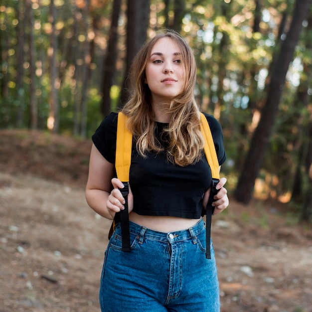 Blonde girl with backpack in forest