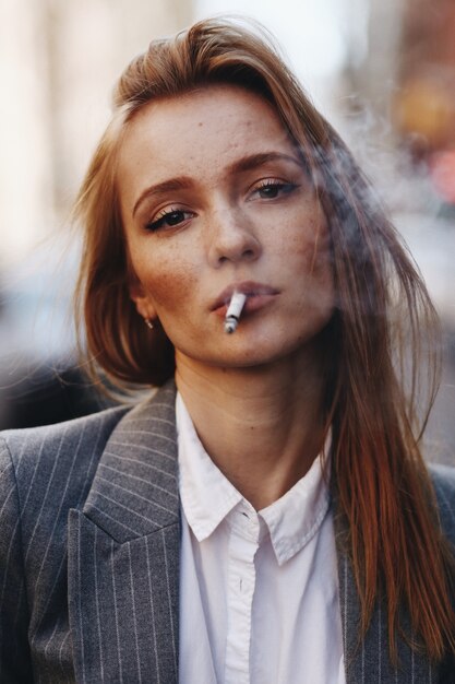 Blonde girl with cigar stands on the street