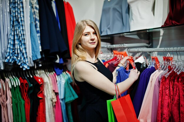 Blonde girl with shopping bags chooses clothes in the boutique