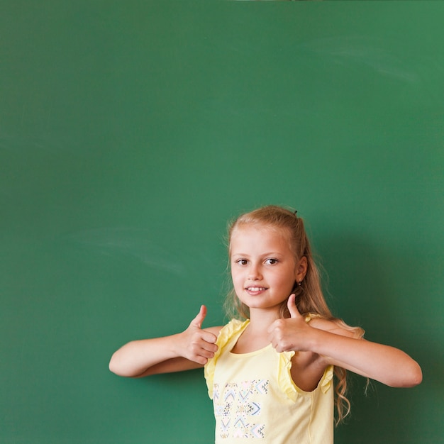 Free photo blonde girl with thumbs up at blackboard