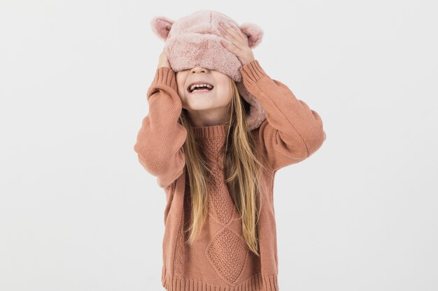 Blonde kid covering his face with winter hat