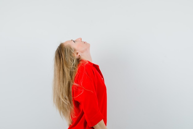 Free photo blonde lady bending head back in red shirt and looking focused. .