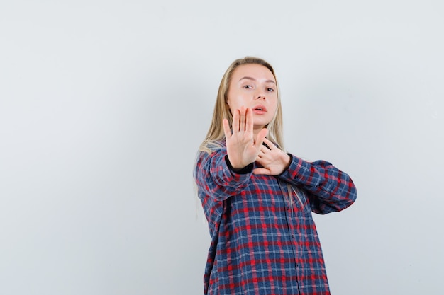 Free photo blonde lady in casual shirt showing stop gesture and looking strict , front view.