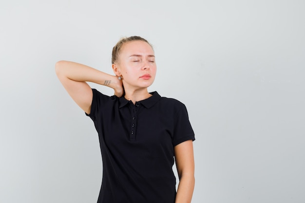 Free photo blonde lady having neck pain in black t-shirt and looking tired , front view.