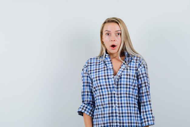 Blonde lady looking at camera in casual shirt and looking astonished